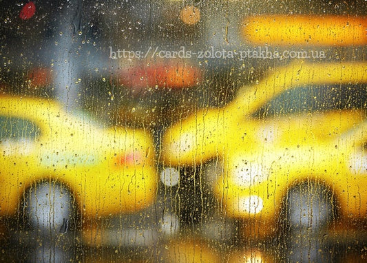 Rain-streaked window with blurred yellow taxis and warm city bokeh