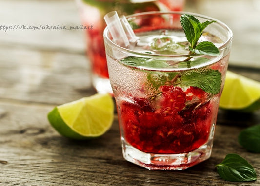 Nahaufnahme eines Himbeer-Mojitos mit Minze und Limette auf Holztisch