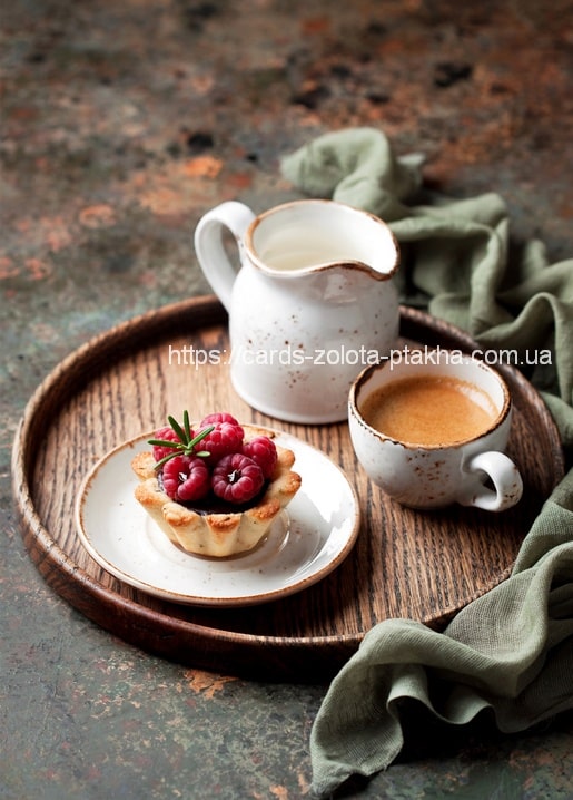 Himbeertörtchen mit Rosmarin, ein Espresso und ein Milchkännchen auf einem Holztablett mit grüner Serviette