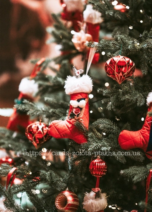 Roter gesteppter Stiefel-Anhänger mit Röschen an einem beleuchteten Weihnachtsbaum