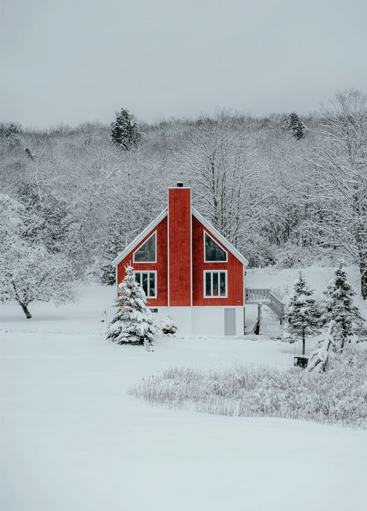 Rotes Giebelhaus steht allein auf einem schneebedeckten Feld