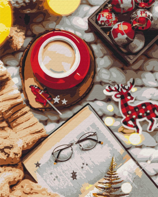 Rote Kaffeetasse, aufgeschlagenes Buch mit Brille und ein karierter Rentier-Anhänger zwischen Lichterketten.