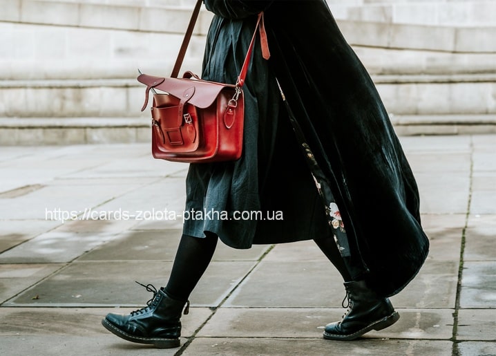 Frau in schwarzem Kleid mit roter Ledertasche und schwarzen Schnürboots