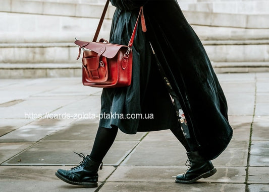 Frau in schwarzem Kleid mit roter Ledertasche und schwarzen Schnürboots