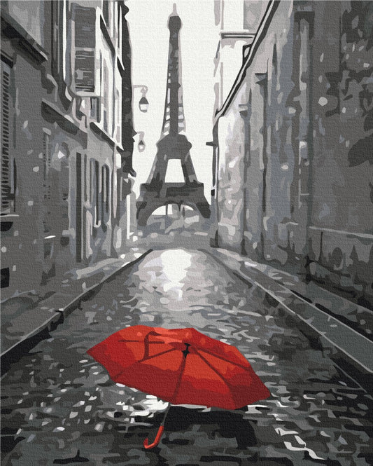 Open red umbrella on a black-and-white Paris street with the Eiffel Tower in the distance