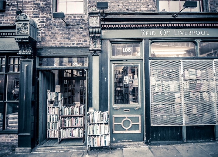 Вивітрений зелений фасад книгарні Reid of Liverpool з книгами на вуличних візках.