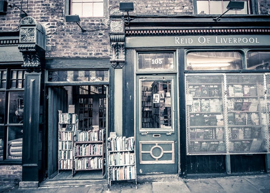 Вивітрений зелений фасад книгарні Reid of Liverpool з книгами на вуличних візках.