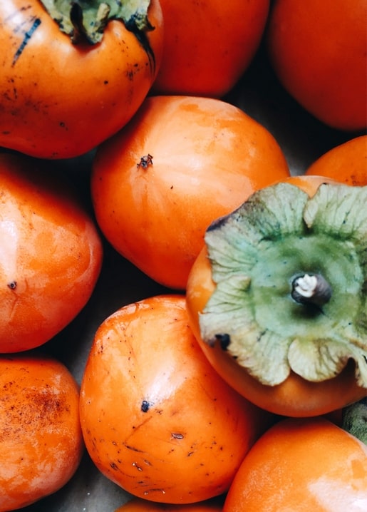 Cluster of ripe orange persimmons with green calyxes, close-up