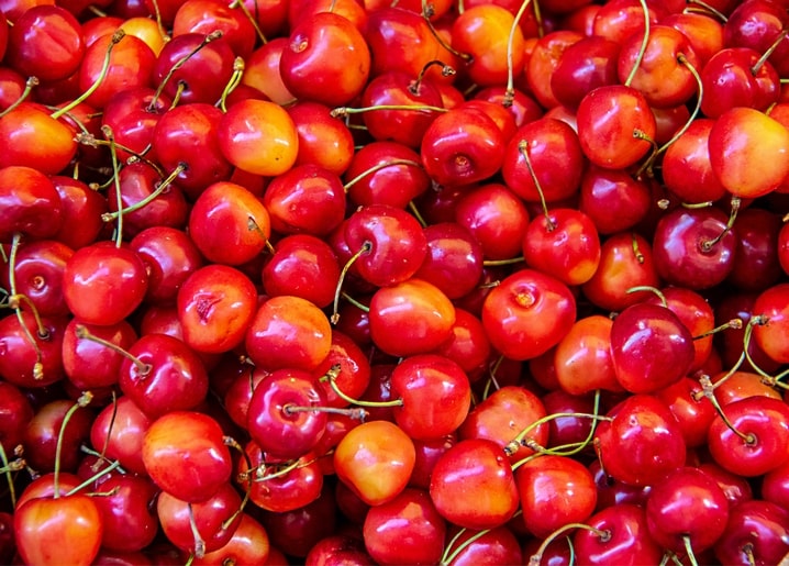 Nahaufnahme eines Haufens glänzender reifer Kirschen in Rot- und Goldtönen