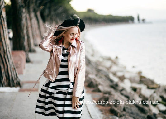 Frau in roségoldener Jacke geht eine Strandpromenade entlang