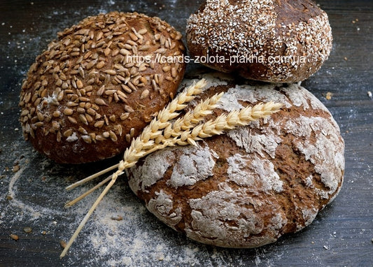 Drei rustikale Brotlaibe mit Sonnenblumenkernen, Hafer und Mehlkruste neben Ährenzweigen.