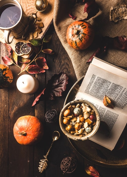 Dark rustic flatlay with pumpkins, a candle, tea and dried citrus slices