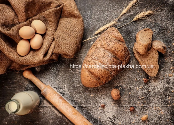Flatlay aus geschnittenem Roggenbrot, Eiern, Milch und Weizenähren auf dunklem Tisch
