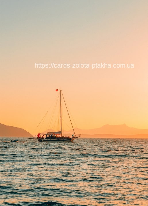 Segelboot auf ruhiger See bei goldenem Sonnenuntergang mit Bergen in der Ferne