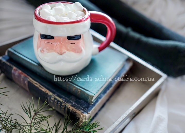 Weihnachtsmann-Tasse mit Marshmallows auf einem Stapel alter Bücher