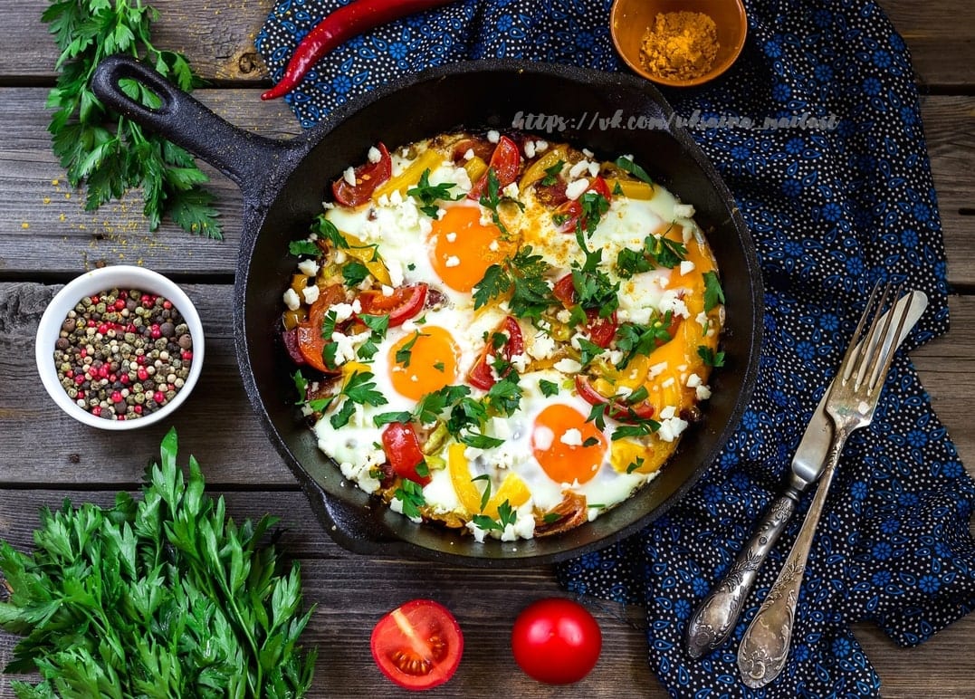Shakshuka eggs baked in tomato sauce with feta in a cast iron skillet