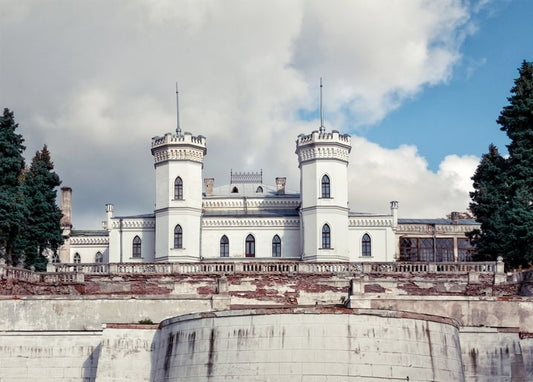 White Gothic Revival towers of Sharivka Palace behind a stone wall