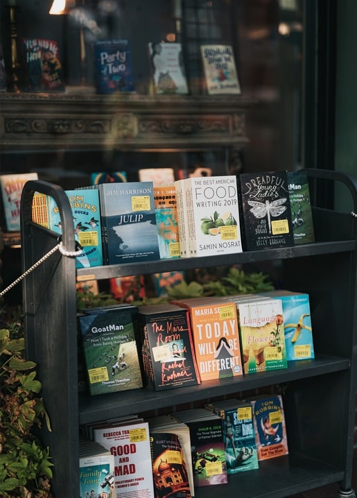 Книги на вуличному візку біля вітрини книгарні у вечірньому світлі