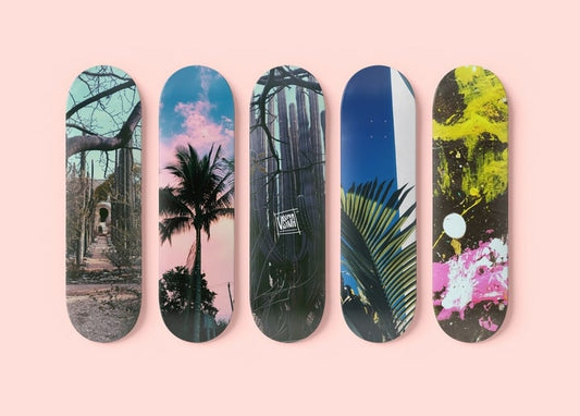 Fünf Skateboard-Decks mit verschiedenen Fotodrucken auf rosa Hintergrund