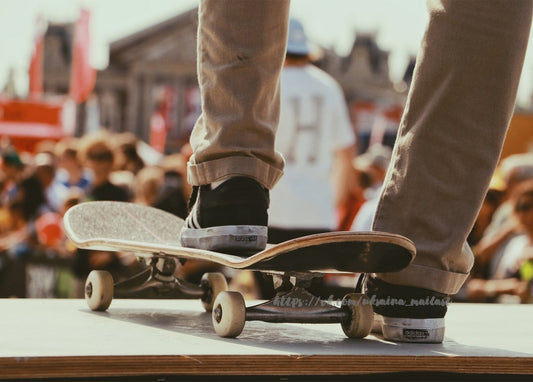 Füße eines Skateboarders balancieren auf dem Board, im Hintergrund eine Menschenmenge
