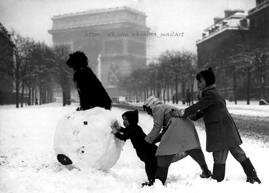Vintages Foto: Kinder rollen einen großen Schneeball mit einem Pudel obenauf, im Hintergrund der Pariser Arc de Triomphe