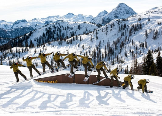 Multi-exposure sequence of a snowboarder jumping a rail in the mountains