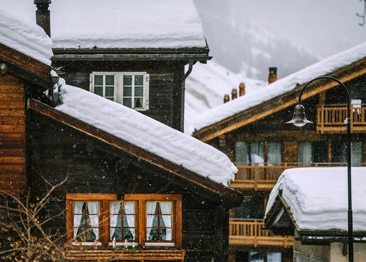 Snow-covered roofs of wooden alpine chalets with a glowing street lamp