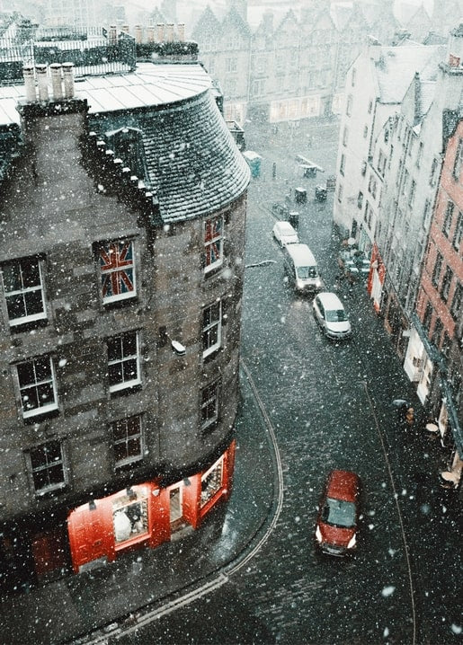Luftaufnahme einer schneebedeckten Altstadtstraße mit rotem Auto