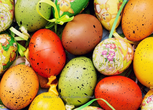 Flat lay of hand-dyed speckled Easter eggs in green, red, brown and yellow with ribbons