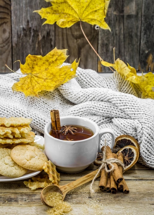 Чашка пряного чаю з корицею, печивом і жовтим кленовим листям