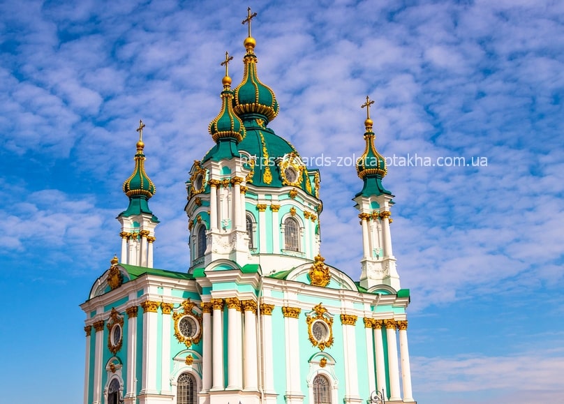 Turquoise and gold domes of St. Andrew's Church rising against a bright blue sky in Kyiv.