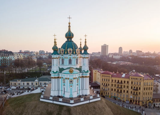 Андріївська церква з бірюзовими банями на заході сонця над Києвом