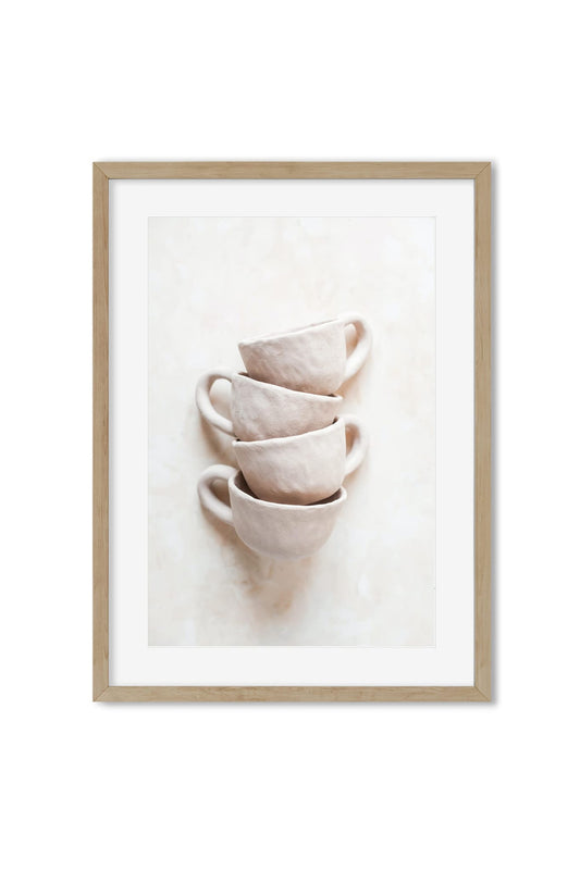 Four pale handmade-style ceramic cups stacked on a neutral background, poster