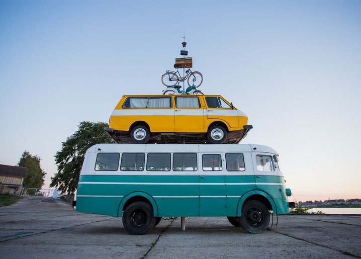 Gelber Vintage-Van auf dem Dach eines türkisfarbenen Busses mit Fahrrad