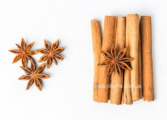 Three star anise pods beside a small bundle of cinnamon sticks on a white background
