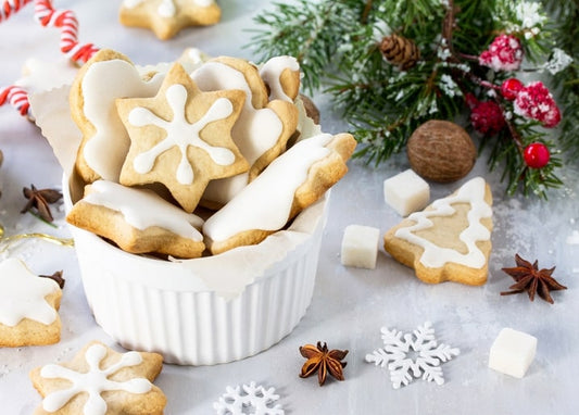 Star and snowflake iced cookies in a bowl with cinnamon, star anise and pine