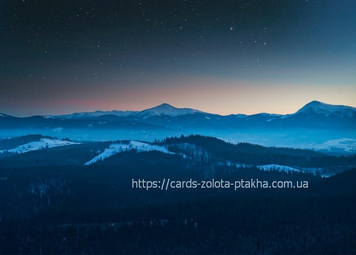 Starry night sky over snow-covered Carpathian mountain ridges near Bukovel
