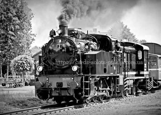 Black-and-white photo of a steam locomotive billowing smoke as it leaves a station