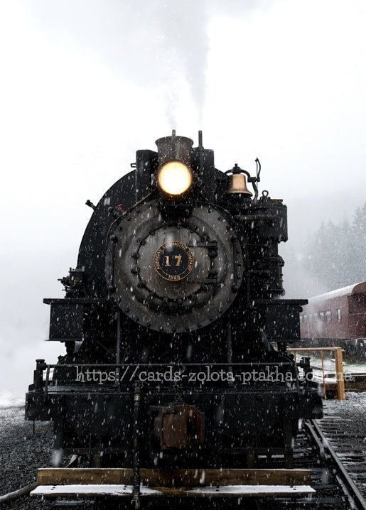 Schwarze Dampflokomotive Nr. 17 mit leuchtendem Scheinwerfer im Schneefall