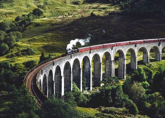 Roter Dampfzug überquert das Glenfinnan-Viadukt in den schottischen Highlands