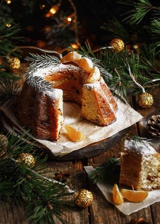 Aufgeschnittener Stollen mit Puderzucker, Mandarinenscheiben und Tannenzweigen