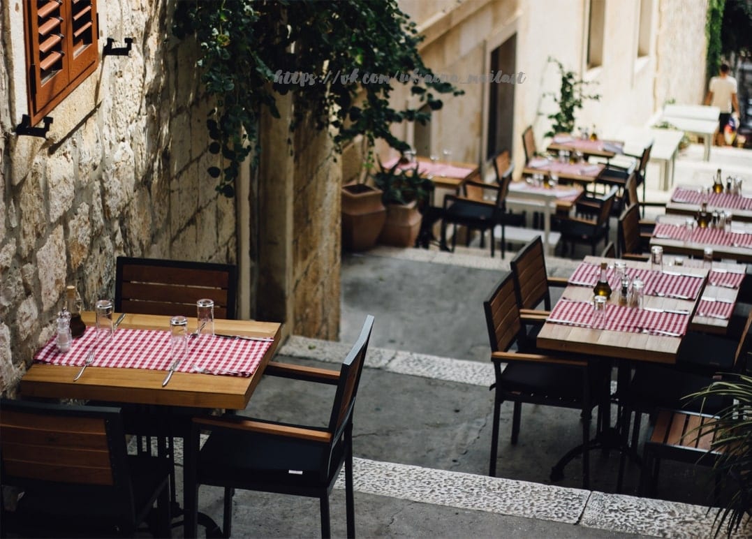 Rot-weiß karierte Tischdecken auf einer Restaurant-Terrasse in einer engen Steingasse