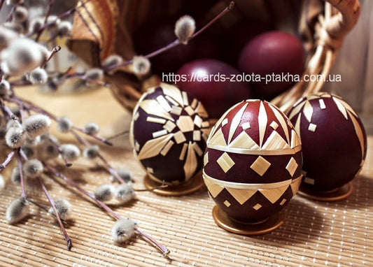 Dark eggs decorated with gold straw appliqué patterns beside pussy willow branches