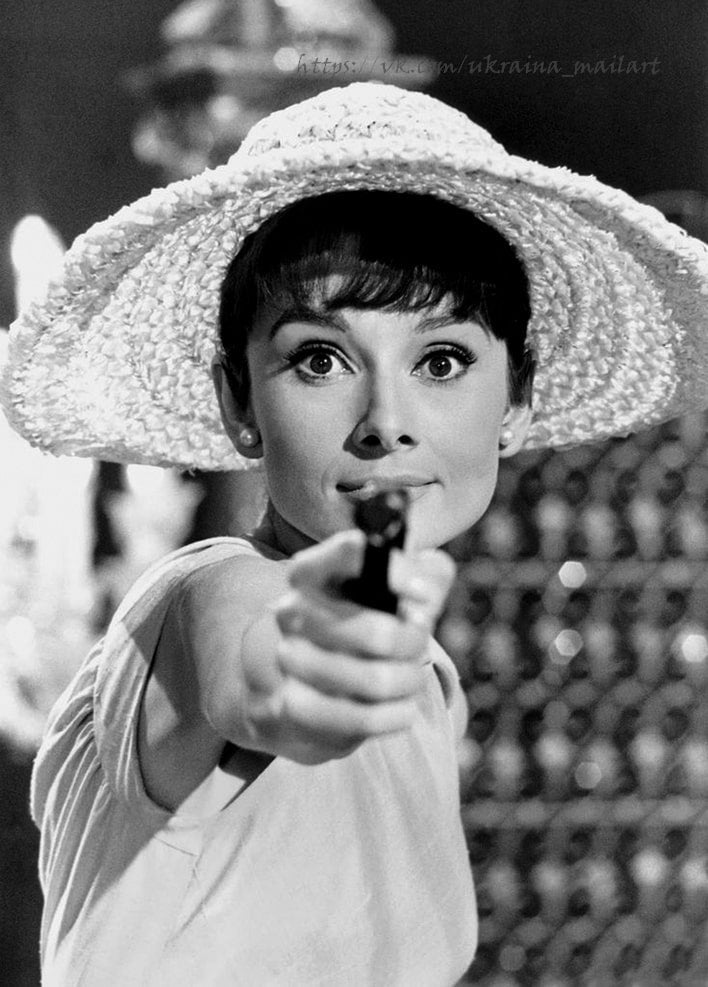 Vintage film still of a woman in a wide straw hat pointing a pistol at the camera