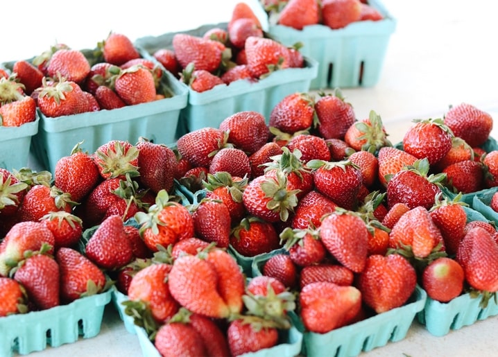 Reife Erdbeeren in türkisfarbenen Pappkörbchen auf einem Marktstand
