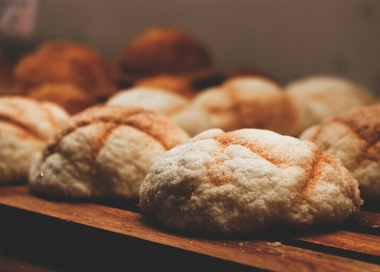 Runde Brötchen mit rissiger Zuckerkruste auf einem Holzbrett