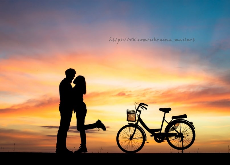 Silhouette eines Paares beim Kuss bei Sonnenuntergang neben einem Fahrrad
