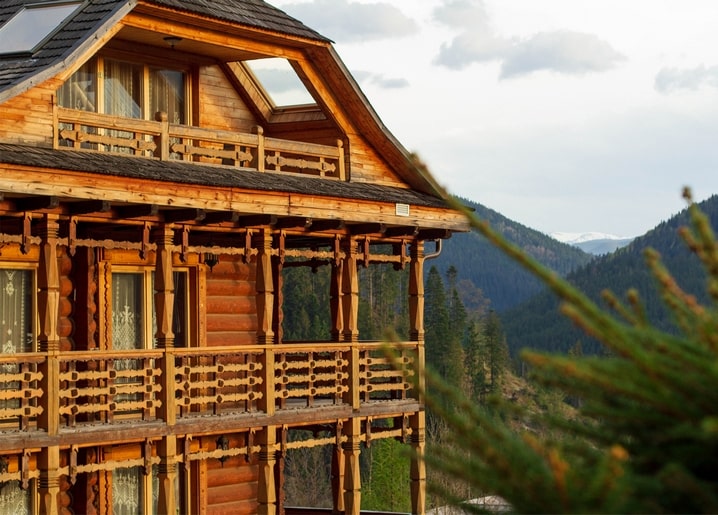 Hand-carved wooden balcony of a guesthouse in Tatariv with Carpathian peaks behind