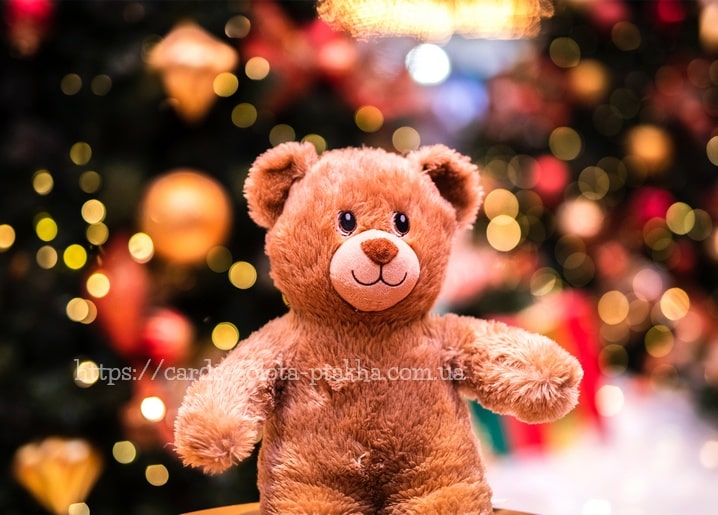 Brauner Teddybär sitzt vor unscharfen goldenen Weihnachtslichtern