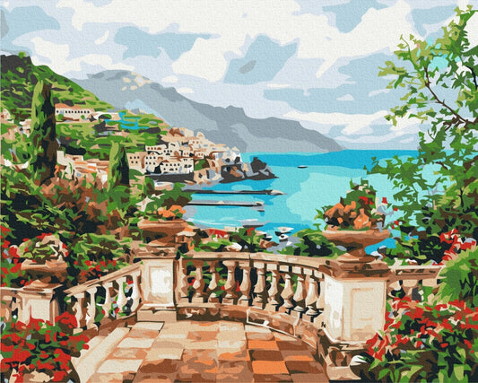 Stone terrace with urns overlooking a turquoise bay, cliffside houses, and mountains
